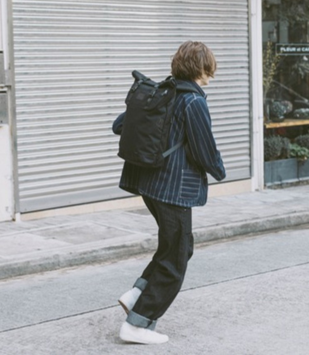 Person mit schwarzem Doughnut Christopher Rolltop-Rucksack auf der Straße
